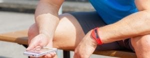 man lookig at his phone to track his fitness also wearing afitness tracker